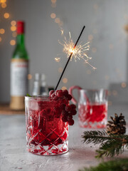 red cocktail with sparkler on gray background