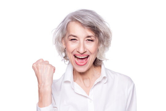 Portrait of a cheerful happy senior woman screaming loudly and gesturing victory with a raised fist isolated over a white background