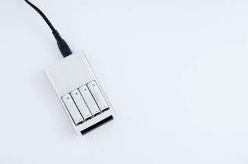 Four AA batteries are charged on  charger. White background.