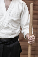 A man holds a wooden jo weapon in his hand