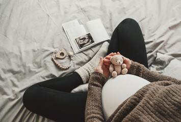 Woman pregnant belly with little teddy toy bear. Concept photo with symbol of many meanings for...