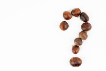 Fresh chestnuts in the form of a question mark on a white background