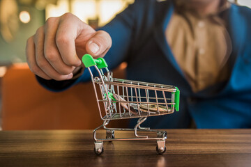 The businessman's hand rolls a shopping cart with bitcoins inside. Cryptocurrency, Business and...