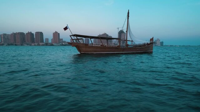  dhows with Qatar Flag in Arabic gulf and Katara skyline in background during Katara eleventh traditional dhow festival in Doha Qatar sunset shot from sailing boat 