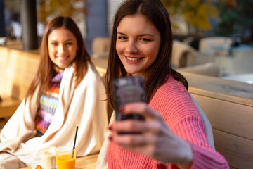 two girls sitting in cafe taking selfie