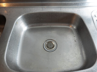 Old and used polished steel kitchen sink in vintage house.