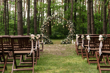 Blooming decoration of wedding arch with roses, carnation and eucalyptus. Beautiful wedding ceremony outdoors. White and pink colors. Wedding photo zone. Floral concept. Wedding details