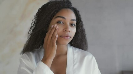 Mirror pov of young attractive african american lady applying moisturizing cream on face, taking care about appearance