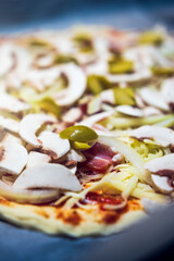 Home-made pizza with .champignons, onion, olives and bacon before baking.
