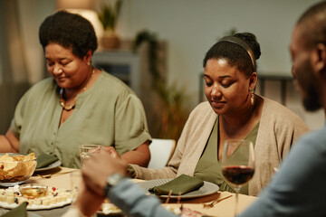 Portrait of African-American family holding hands while saying grace during dinner party at home