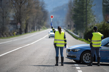 Italian Police controls on the road. Officers with masks and gloves monitor passing motorists. Street control for the Covid-19 with a policewoman. Police checkpoint. - obrazy, fototapety, plakaty