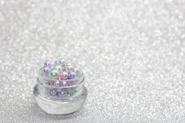 Fototapeta na wymiar Jar full of pearls on glitter background