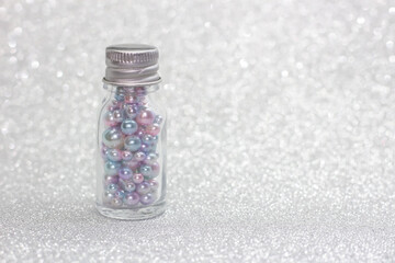 Bottle full of pearls on glitter background