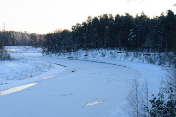 beautiful sunset over the river with snowy trees in winter