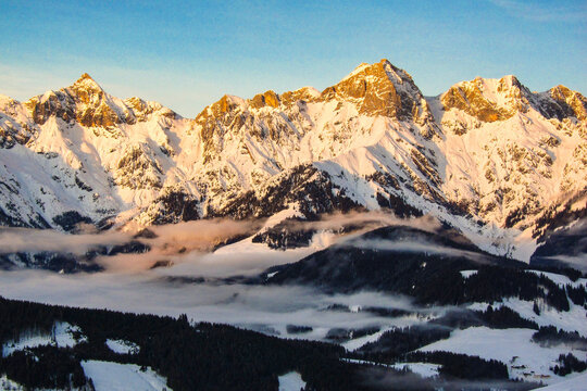 Sunrise in Maria Alm, Hinterthal in Austria. Winter landscape, stunning mountain range, snowy trees and blue sky