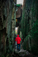 Man hiking through Kungsklyftan canyon with mossy rocks by village Fjällbacka in Sweden.