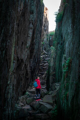 Woman hiking through Kungsklyftan canyon with mossy rocks by village Fjällbacka in Sweden.