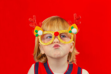 portrait of child boy wearing christmas carnival glasses on a red background