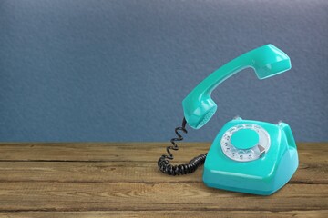 Retro rotary telephone on table front concrete wall background. Vintage old style