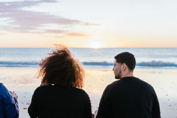 Back of two friends gazing the horizon of the sea during sunset