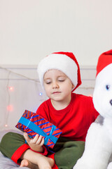Portrait of a cute boy in a Santa Claus hat. Funny smiling child. Gifts, toys, joy, celebration.