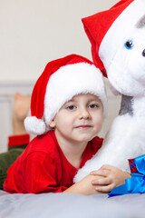 Portrait of a cute boy in a Santa Claus hat. Funny smiling child. Gifts, toys, joy, celebration.