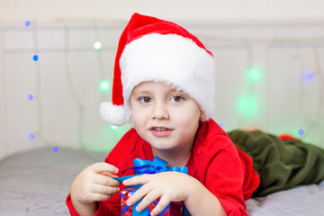 Portrait of a cute boy in a Santa Claus hat. Funny smiling child. Gifts, toys, joy, celebration.