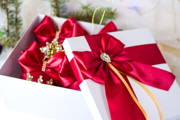 A Christmas gift decorated with a beautiful bow on a light background with a fir twig. Gifts, joy, surprise. Selective focus. the concept of Christmas and New Year