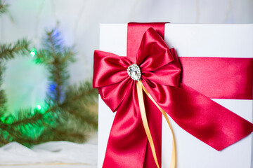 A Christmas gift decorated with a beautiful bow on a light background with a fir twig. Gifts, joy, surprise. Selective focus. the concept of Christmas and New Year