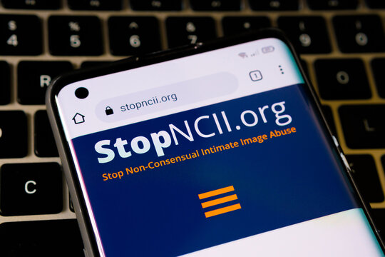 Stopncii.org web site seen on the smartphone placed on a laptop keyboard. Organization to Stop Non-Consensual Intimate Image Abuse. Stafford, United Kingdom, December 5, 2021.