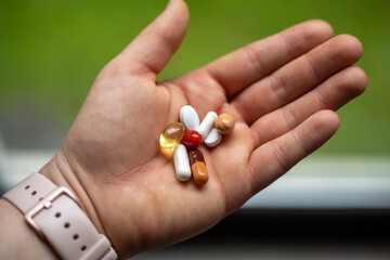 a handful of pills and capsules in the palm of your hand.