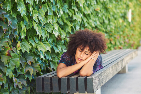 A beautiful woman lying in a park.She has beautiful afro hair.