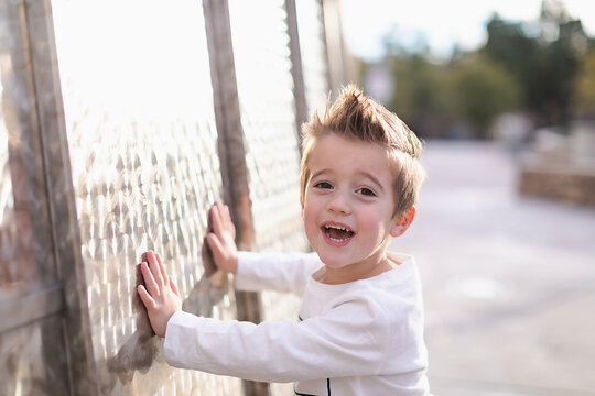 Smiling young preschooler boy touching a metal wall.