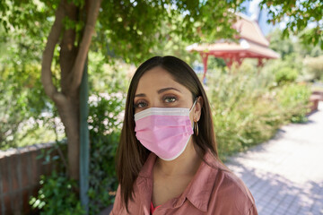 A beautiful white Latina woman close up wearing face mask amid the cor