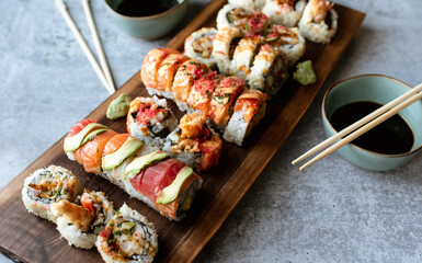 Overhead view of platter of sushi rolls on gray cement background.