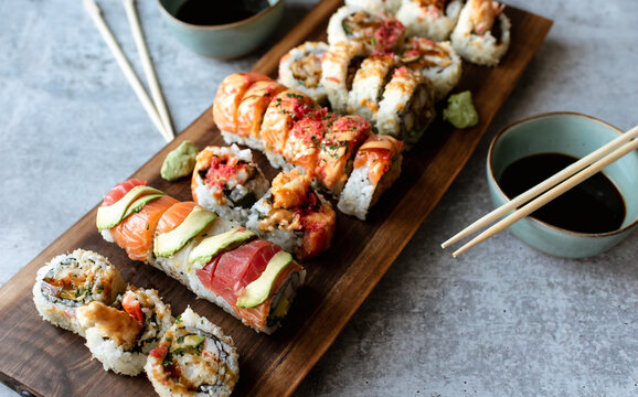 Overhead view of platter of sushi rolls on gray cement background.