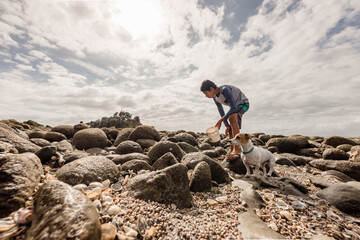 Young teen boy looking for shells with dog on New Zealand coast