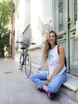 Happy woman while sitting by bicycle outside building