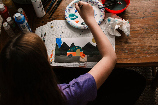 Photo from above of a girl painting a camping scene
