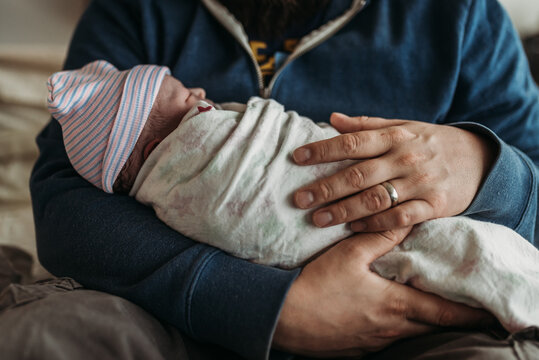 Close up image of fathers hands holding newborn son right after