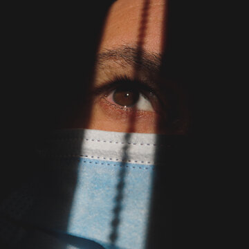 man with mask in the shadows showing the brown eye
