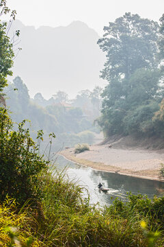 man rowing boat on still river in Laos