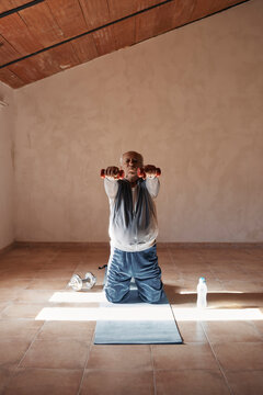 An Older Man Is Doing Stretching Exercises With Weights At Home