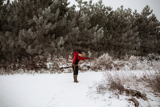 Teen boy shooting bow and arrow in wintery Wisconsin field
