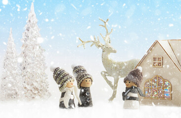 Christmas fairy tale on a snowy background, family concept. House with Christmas lights, reindeer, ice trees and cute gnomes. Close-up.