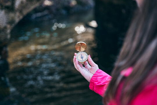 Girl Hand with compass at mountain road for better orientation.