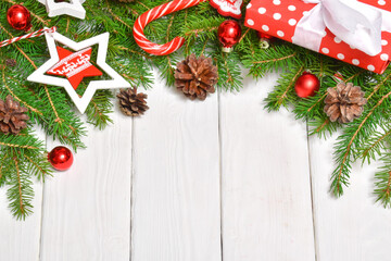 Festive background with a Christmas tree gift and candy cane on a white wooden table. Copy space. Flat lay, top view.