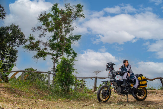 Woman posing on his scrambler type off road motorcycle in Thailand