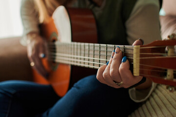 Close-up of a middle-aged woman playing the guitar. Music learning