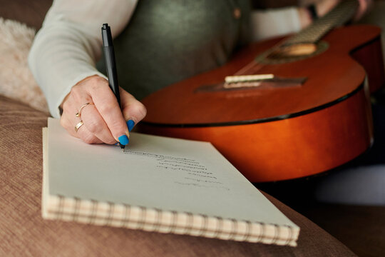 Close-up of a middle-aged woman writing in a notebook. Music learning